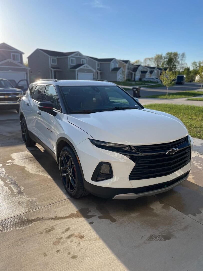 A white suv parked in the driveway of some houses.