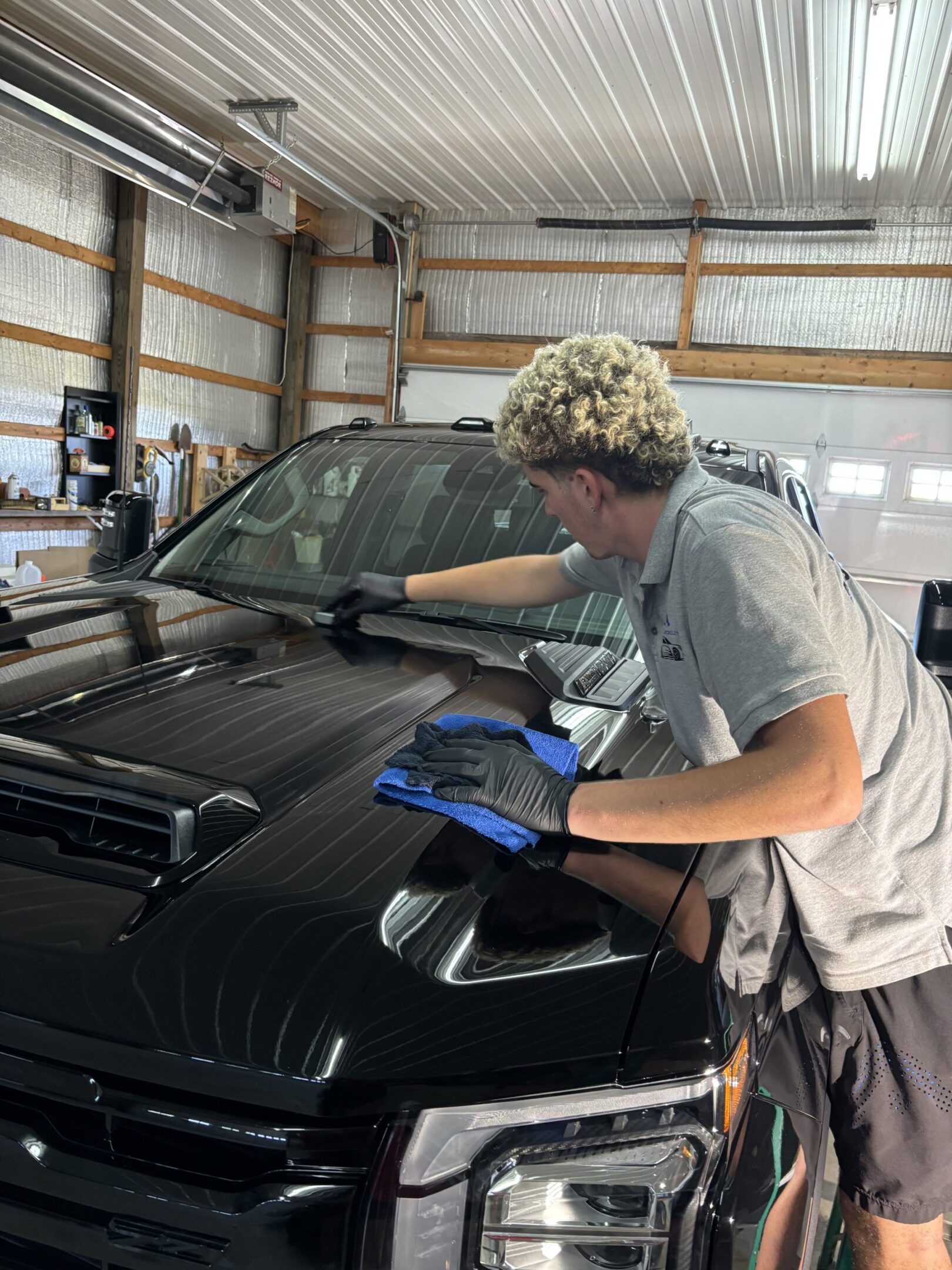 A man is working on the hood of his car.