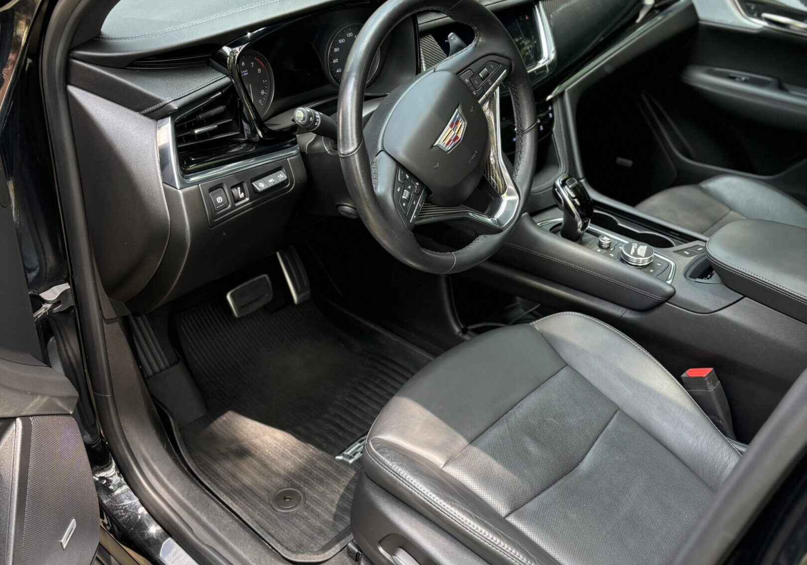 A car with black leather seats and the door open.